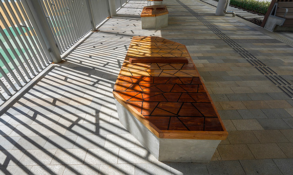 我們邀請了數位香港藝術家及資深工匠取材自皇后山軍營保留下來的木材，設計及創作多元類型的木凳，並悉心裝置於屋邨內各個位置。